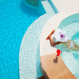 women in white hat relaxing in luxury pool